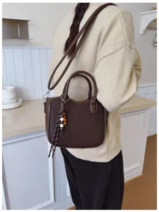 Detailansicht der eleganten braunen Flechtmuster Umhängetasche mit schönen Holzperlen.