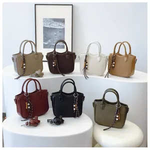 Detailansicht mehrfarbiger gewebter Damenhandtaschen mit Perlenanhänger und Riemen.