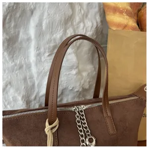 Braune Wildleder Handtasche Detail mit Metallreißverschluss und schickem Kettendekor.