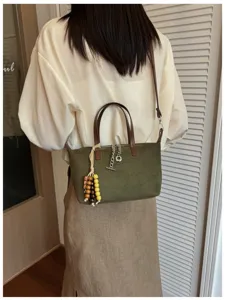 Olivgrüne Wildleder Umhängetasche Detail mit Holzperlen Anhänger und schicker Metallkette Dekor.
