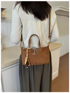 Detailansicht der braunen Wildleder Umhängetasche mit Perlenanhänger und Metallreißverschluss.
