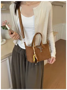 Detailansicht braune Wildleder Umhängetasche mit Perlenquaste und Kette für Damen.