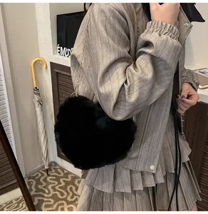Detailed view of a stylish black faux fur heart-shaped crossbody bag with a chain strap for women.