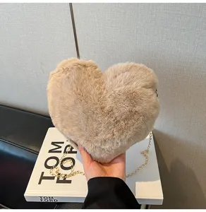 Fuzzy heart-shaped cross-body bag detail view, soft plush material with gold chain strap.