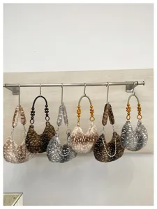 Vue détaillée de sacs hobo en peluche avec motifs animaliers, poignées perlées et chaînes.