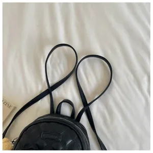 Vue détaillée d'un mini sac à dos matelassé noir avec des bretelles en forme de cœur.