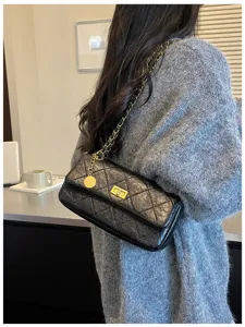Detail view of the elegant black quilted leather shoulder bag with a gold chain and lock.