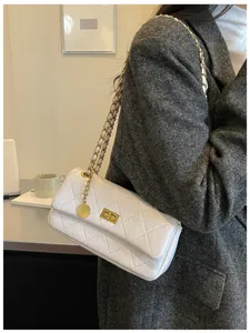 Detailed view of women white quilted shoulder bag with gold chain strap and chic turn lock.