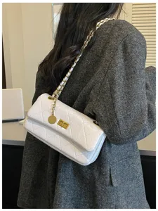 Quilted white shoulder bag detail showing classic gold chain strap and turn lock closure.