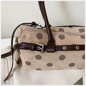 Close-up of stylish polka dot suede shoulder bag featuring brown handle and metal buckle detail.