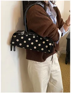 Detailed shot of a stylish black and white polka dot baguette shoulder bag worn daily.