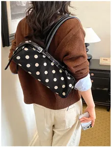 Detailed view of the stylish black and white polka dot shoulder baguette bag in a chic daily outfit setting.