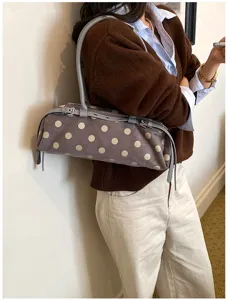 Detailed close-up of the stylish polka dot shoulder bag featuring strap and metal grommet accents.