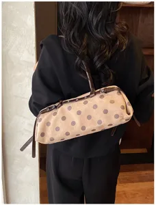 Detailed view of a stylish polka dot baguette shoulder bag with leather straps worn by model.