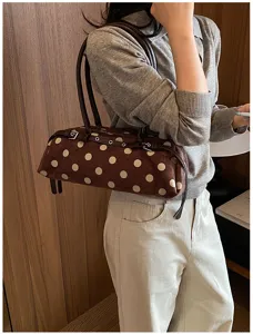 Detailed close-up view of brown polka dot shoulder bag with dual straps and chic design.