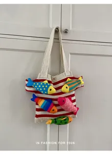 Vue détaillée d'un sac cabas tricoté à rayures avec décorations de poissons en peluche. Style.