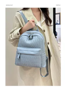 Detail view of a light blue leather backpack showcasing fine texture, zippers, and style.