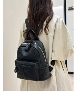 Detailed view of black leather women backpack with quilted texture and double zippers.