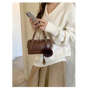 Vue détaillée d'un sac Boston marron en cuir avec pompon duveteux et style chic pour le quotidien.