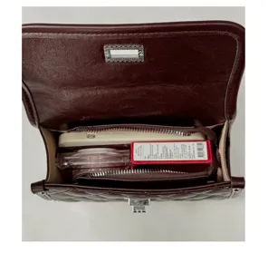 Detailansicht des inneren Fassungsvermögens der dunkelbraunen gesteppten Tasche mit Fächern.