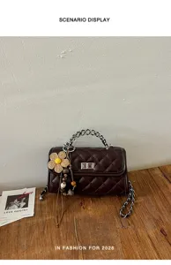 Klassische gesteppte Umhängetasche aus Leder mit Kettengriff und blumigem Anhänger.