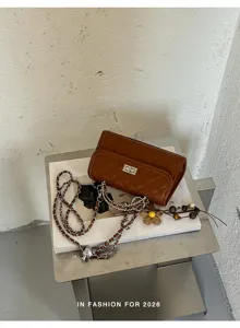 Stilvolle gesteppte Umhängetasche für Damen mit Metallkette und schickem Blumenanhänger.