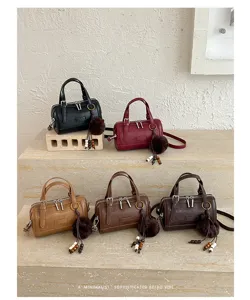 Détail de sac Boston avec options multicolores, pendentif en peluche et cuir PU.