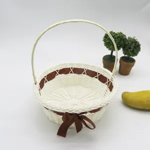Panier de fleurs tisse en rotin synthetique blanc avec noeud marron pour decoration de mariage.