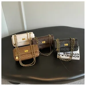 Detailed view of fashionable quilted chain shoulder bags in various colors on dark table setup.