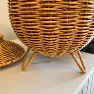 Detailed view of handmade imitation rattan woven storage basket with lid and tripod legs.