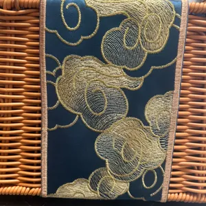 Hand-woven rattan basket detail with exquisite gold embroidered auspicious cloud pattern fabric.