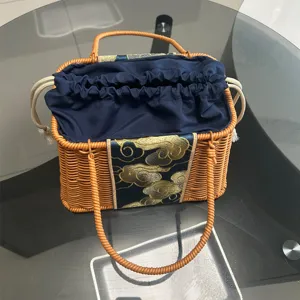 Woven rattan basket bag detail showing dark blue drawstring inner lining and golden cloud embroidery.