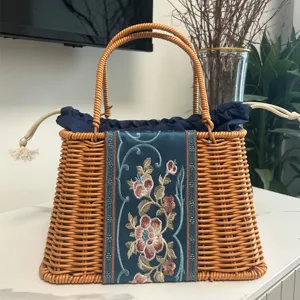 Handmade woven rattan handbag with elegant floral embroidery and blue drawstring lining for women.