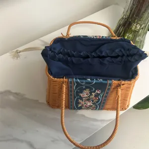 Handmade woven rattan handbag with blue embroidered fabric and drawstring lining for daily use.
