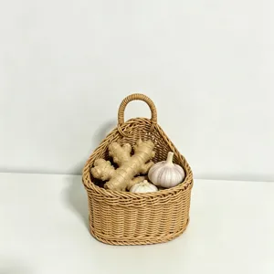 Close-up detail of the woven hanging storage basket holding ginger and garlic in kitchen scene.