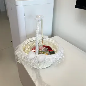 Vista dettagliata del cestino di fiori in rattan bianco con delicato pizzo e bel fiocco.