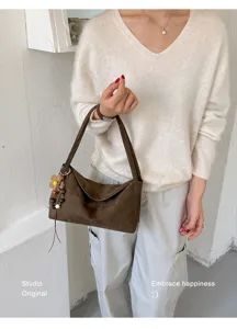 Brown suede underarm shoulder bag with cute flower pendant, chic everyday accessory.