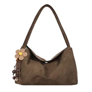 Brown suede shoulder bag for women, stylish underarm tote with cute flower pendant.