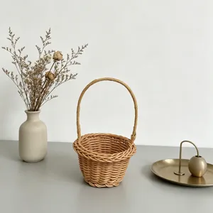 Gros plan detail d'un petit panier de fleurs en rotin tisse avec poignee sur table, rustique.