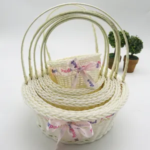 White imitation rattan nested flower basket detail, woven storage basket with pink ribbon bow.