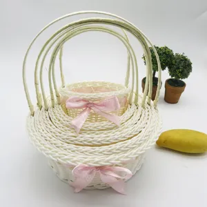Detailed view of nested white woven wicker flower baskets with pink bows for storage.