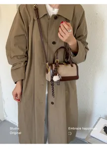 Vintage bolso de hombro cilíndrico de lona y cuero con correa larga y bonito colgante.