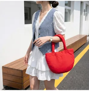 Detailaufnahme einer roten gesteppten Puffer-Shopper-Tasche mit weicher Textur.