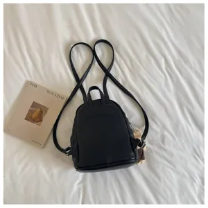 Petit sac à dos noir pour femme, design matelassé élégant avec bretelles doubles.