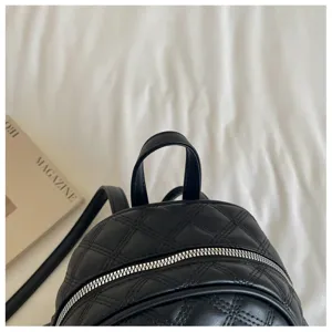Détail du sac à dos matelassé noir, similicuir de qualité, fermeture éclair métallique élégante.