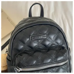 Mini sac à dos matelassé en cuir synthétique noir avec une poche zippée à l'avant.
