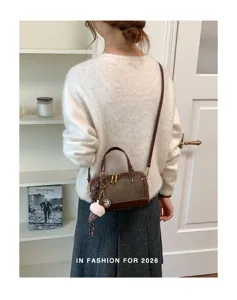 Vista detallada del bolso vintage marron con asas dobles y un encantador llavero de felpa suave.