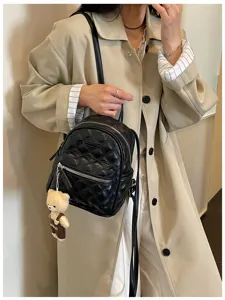Détail du mini sac à dos noir matelassé avec motif losanges et joli pendentif ours.