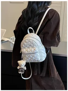 Détail de sac à dos matelassé blanc avec motif en losanges et joli pendentif d'ours