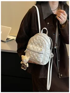 Vue détaillée d'un mini sac à dos matelassé blanc chic avec pendentif ours et bretelles.